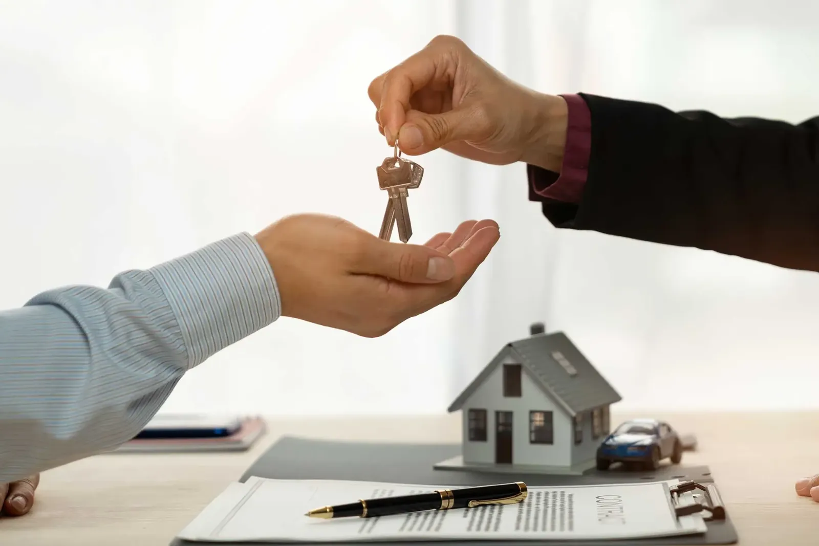 Une main qui tend des clés d'une maison à une autre main